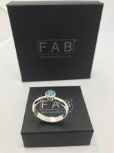 Load image into Gallery viewer, Deep blue Topaz solitaire ring made with a Sterling silver D shaped shank shown sat upright on jewellery box.