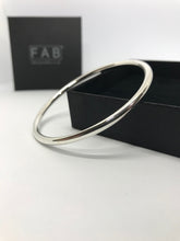 Load image into Gallery viewer, 925 Sterling Silver plain finish bangle, shining in the light, resting on its own supplied jewellery box. Made by hand in Cornwall, from 4mm thick solid silver wire.