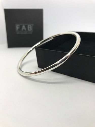 925 Sterling Silver plain finish bangle, shining in the light, resting on its own supplied jewellery box. Made by hand in Cornwall, from 4mm thick solid silver wire.