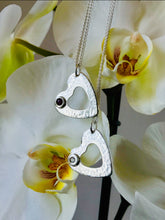 Load image into Gallery viewer, Handmade Hammered Texture Sterling Silver Pendants And Chains, One With A Ruby And One With A CZ, Hanging From A Orchid Plant.