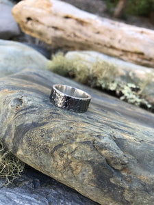 Camo mens 925 Sterling Silver textured oxidised ring sat upon the rocks in Cornwall.