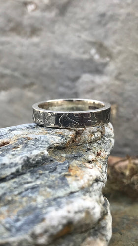 Sterling Silver Women's etched and oxidised ring perched on a rock.